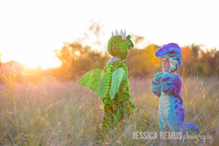 two boys in dinosaur costumes in field