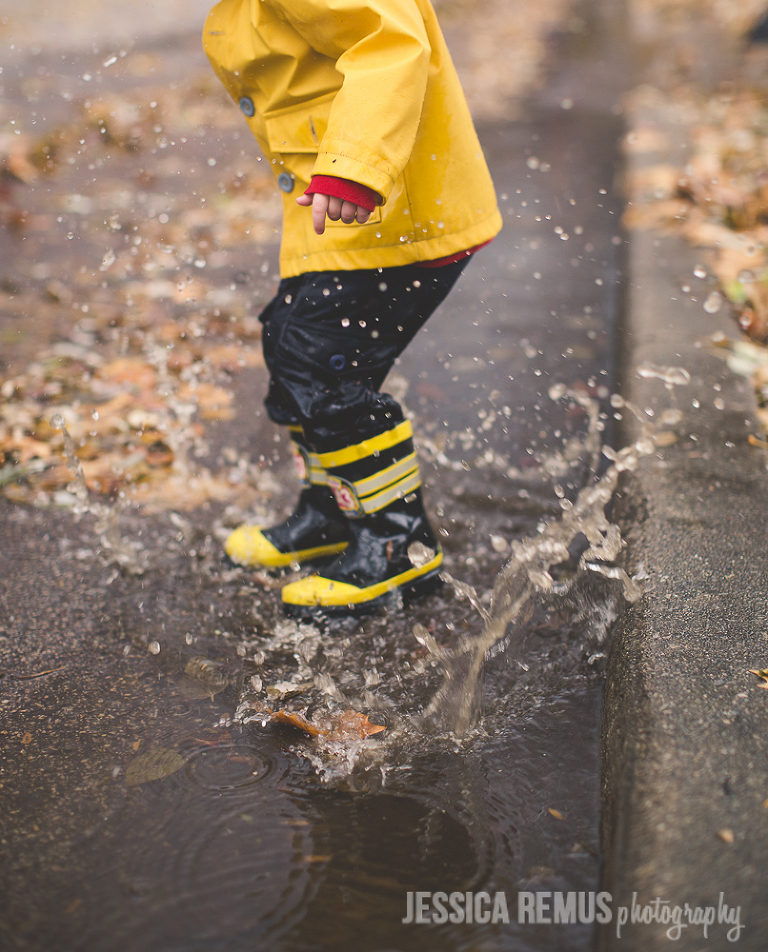 toddler splashing in rain in street