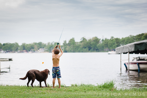 boy fishing with dog at lake